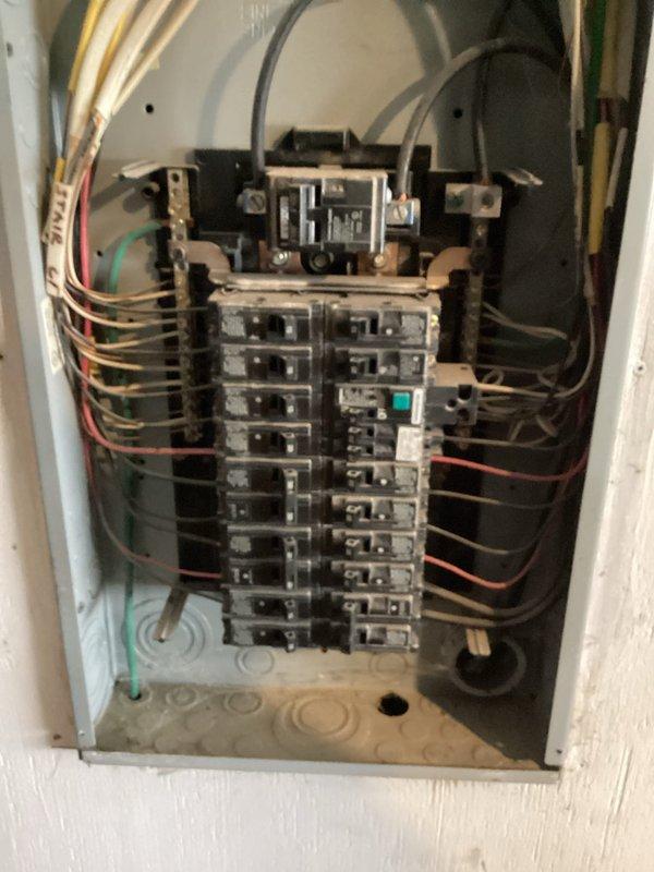 Responded to service call for electrical panel wiring repair identified during home inspection. Upon arrival, accessed and inspected main electrical panel box containing dual rows of circuit breakers and main disconnect assembly. Corrected improper wire connection in panel as flagged by inspection report. Verified all circuit breaker connections, bus bar integrity, and grounding wire terminations met current electrical code requirements. Documented panel condition with photographs showing before and after states of repair work performed.