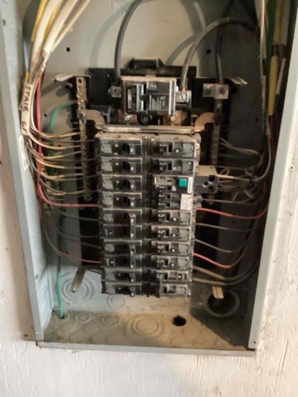 Responded to service call for electrical panel wiring repair identified during home inspection. Upon arrival, accessed and inspected main electrical panel box containing dual rows of circuit breakers and main disconnect assembly. Corrected improper wire connection in panel as flagged by inspection report. Verified all circuit breaker connections, bus bar integrity, and grounding wire terminations met current electrical code requirements. Documented panel condition with photographs showing before and after states of repair work performed.