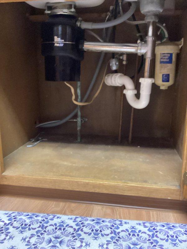 Completed garbage disposal replacement in kitchen under double-basin sink with hardwired electrical connection. Replaced existing disposal unit with new black disposal, ensuring proper mounting and connection to white PVC drain assembly and P-trap configuration. Installation included verifying proper alignment with sink drain opening, securing disposal to mounting ring, and completing straight-wire electrical connection. Provided estimate for potential future work on sink and faucet replacement.