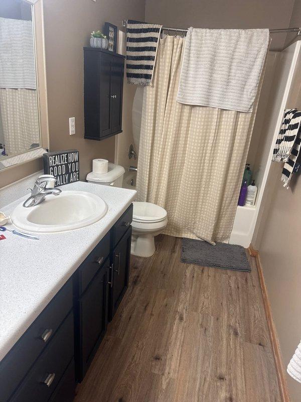 Responded to service call for reported water under carpet and flooring in bathroom. Upon arrival, conducted thorough inspection of bathroom area including vanity, toilet, tub/shower combination, and surrounding flooring. Examined wood-look laminate flooring for moisture damage and investigated potential leak sources. Assessed plumbing fixtures including dual sink vanity with chrome faucets, toilet, and tub/shower plumbing for visible leaks or water intrusion. Determined wet carpet condition was result of ground water infiltration rather than plumbing system failure. No active leaks detected from supply lines, drain lines, or fixture connections. Documented conditions with photographs for service records.