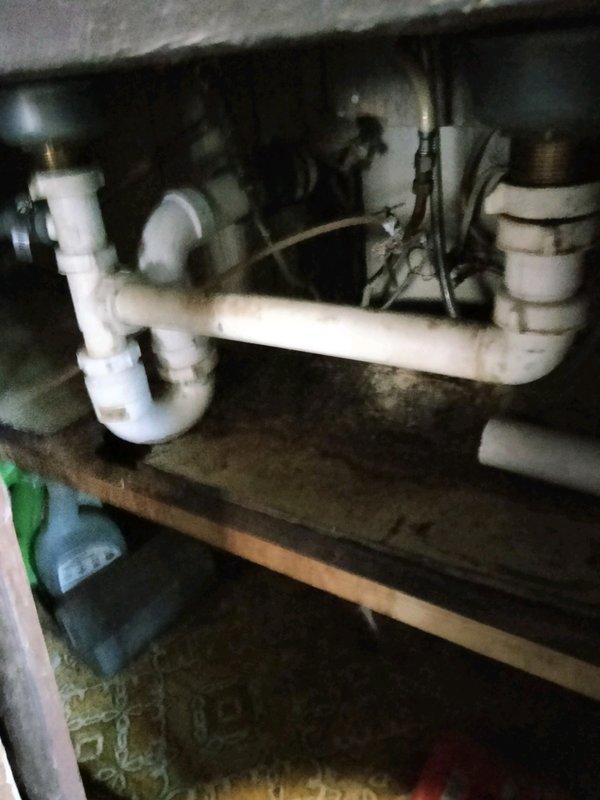 Responded to service call for water heater expelling steam and clogged kitchen sink. Upon arrival, inspected 30-year-old 40-gallon LP atmospheric vent water heater and found unit had sunk into severely rotted subfloor, causing vent pipe to detach from appliance. Red tagged water heater due to improper venting creating unsafe condition and potential carbon monoxide hazard. Assessed kitchen sink drain system and confirmed clog requiring clearing. Documented conditions with photographs showing compromised structural flooring beneath water heater, deteriorated wood framing, and sink drain configuration. Provided estimate for water heater replacement with new 40-gallon LP atmospheric vent unit including necessary subfloor repair, and separate estimate for kitchen sink drain clearing service.