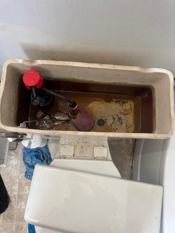 Responded to service call for toilet that was running constantly and experiencing double flushing issues. Upon arrival, inspected toilet tank and identified broken flush handle as primary cause of malfunction. Tank interior showed significant rust staining, mineral deposits, and corroded flush valve assembly, indicating age-related deterioration of internal components. Replaced defective flush handle with new unit to restore proper flushing operation and eliminate continuous running condition. Tested flush mechanism after installation to verify proper function and confirm resolution of reported issues.