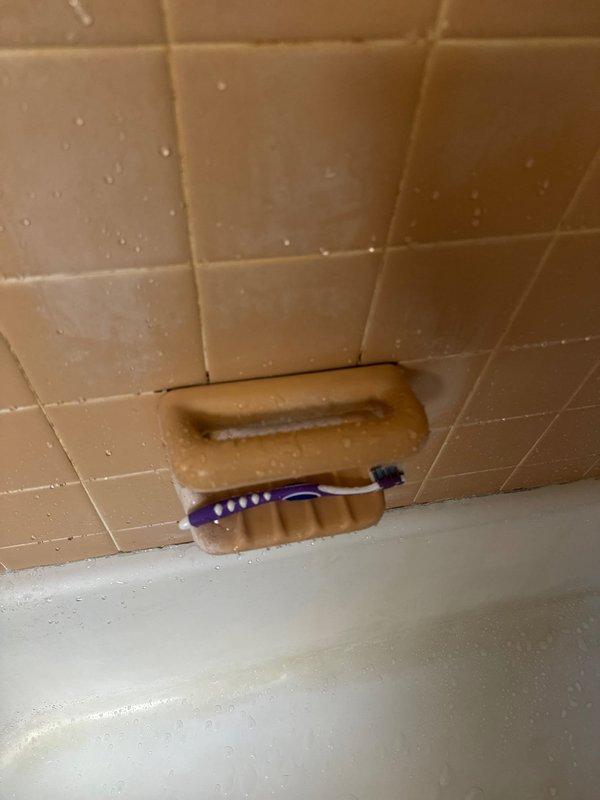 Responded to service call for suspected ductwork leak with rusty-colored water discharge in bathroom ceiling area. Upon investigation, determined leak originated from bathroom soap shelf rather than HVAC system. Applied silicone sealant around soap shelf to prevent water intrusion and replaced small damaged section of return air ductwork that had been affected by moisture exposure.