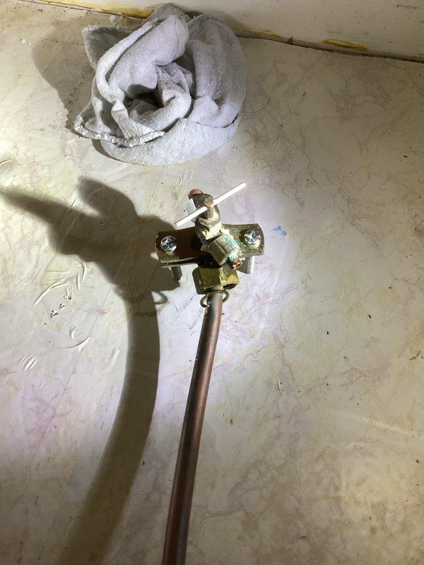 Responded to service call for leaking saddle valve on cold water supply line. Upon inspection, identified active leak at saddle valve connection point on vertical PVC cold water pipe. Removed defective saddle valve and replaced with new brass shut-off valve assembly featuring dual copper pipe connections and manual control handle. Tested installation for proper operation and verified no leaks present after replacement.
