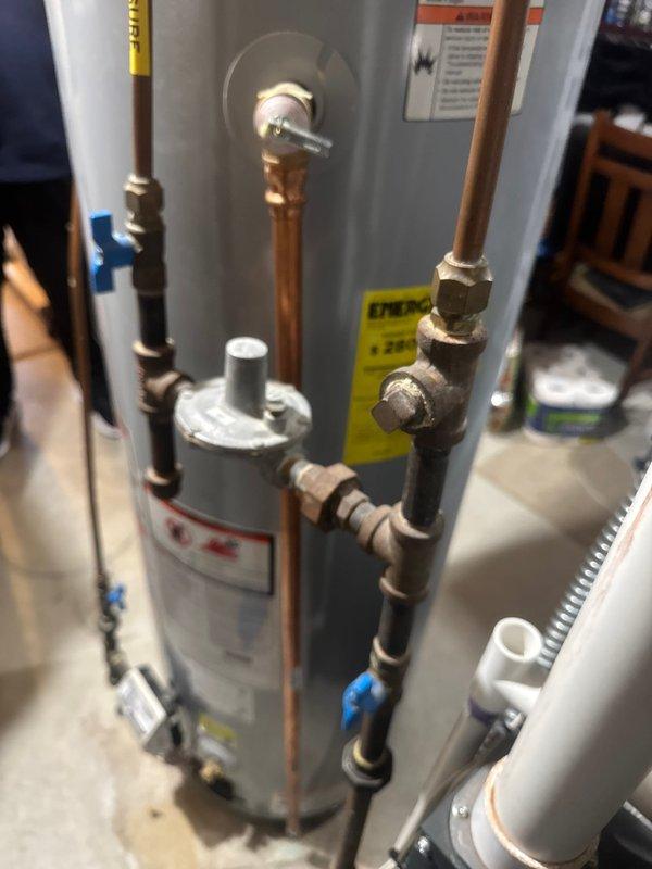 Responded to service call for gas water heater with pilot light ignition issues. Upon arrival, found pilot light extinguished and unit non-operational. Successfully relit pilot assembly and restored temporary hot water service to residence. Conducted thorough diagnostic assessment of gas control valve and burner assembly due to recurring pilot outage concerns. Photographic documentation captured existing installation showing aged copper supply lines, oxidized fittings, and water accumulation in drip pan beneath unit, indicating potential leak concerns requiring monitoring. Provided comprehensive estimate for conversion from gas-fired to electric water heater replacement per customer request, with customer enrolled in rewards program for applicable installation discount. Unit returned to operational status pending customer decision on replacement installation.