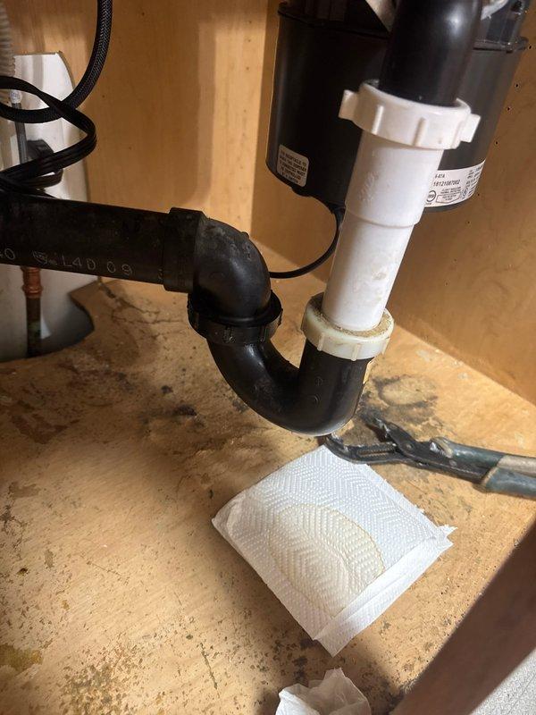 Responded to callback for newly installed sink with dripping leak from unknown source. Upon arrival, inspected underside of kitchen sink and identified leak originating from loose P-trap connection beneath garbage disposal. Tightened drain trap assembly to proper torque specifications, securing connection between disposal outlet and PVC drain line. Verified all connections were secure and tested system for leaks. No further dripping observed after repair.