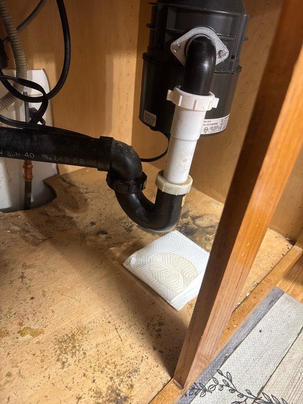 Responded to callback for newly installed sink with dripping leak from unknown source. Upon arrival, inspected underside of kitchen sink and identified leak originating from loose P-trap connection beneath garbage disposal. Tightened drain trap assembly to proper torque specifications, securing connection between disposal outlet and PVC drain line. Verified all connections were secure and tested system for leaks. No further dripping observed after repair.