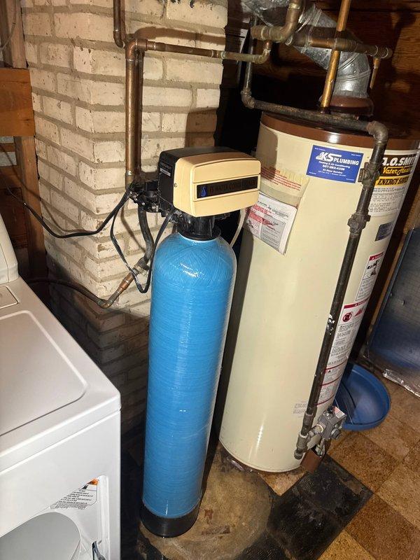 Responded to service call for water heater leak and water softener malfunction. Upon arrival, identified brine tank overflow condition on water softener system causing excess water discharge. Documented equipment setup including water heater, water softener with control head, and associated copper piping connections. Assessed brine tank failure requiring full replacement due to overflow malfunction. Collected diagnostic fee and captured photographic documentation of affected equipment and overflow condition for service records.