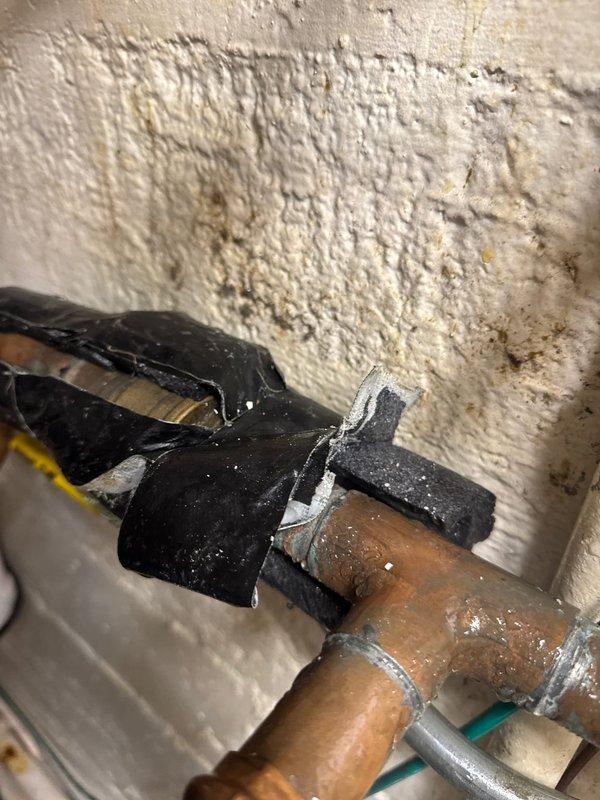 Responded to emergency call for water main leak. Upon arrival, identified pinhole leak in aged copper piping with deteriorated temporary repair tape from previous patch attempt. Pipe showed significant oxidation and corrosion consistent with extended service life. Applied temporary patch to stop active dripping and stabilize the compromised section until permanent repair can be scheduled. Customer advised that full pipe replacement recommended due to advanced deterioration of copper line and multiple stress points visible along the run.