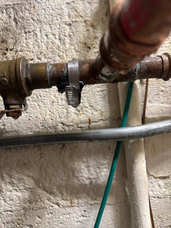 Responded to emergency call for water main leak. Upon arrival, identified pinhole leak in aged copper piping with deteriorated temporary repair tape from previous patch attempt. Pipe showed significant oxidation and corrosion consistent with extended service life. Applied temporary patch to stop active dripping and stabilize the compromised section until permanent repair can be scheduled. Customer advised that full pipe replacement recommended due to advanced deterioration of copper line and multiple stress points visible along the run.
