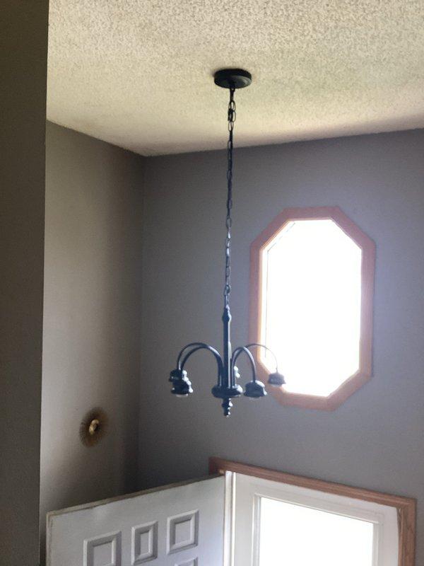 Responded to service call for light fixture installation assistance. Homeowner had removed existing fixture but was unable to complete installation of new three-arm chandelier-style fixture. Successfully mounted and hung new black chandelier fixture from ceiling, securing all electrical connections and chain support. During testing, diagnosed faulty wall switch preventing proper fixture operation. Homeowner elected to replace switch independently and will complete installation of light globes and bulbs after switch repair.