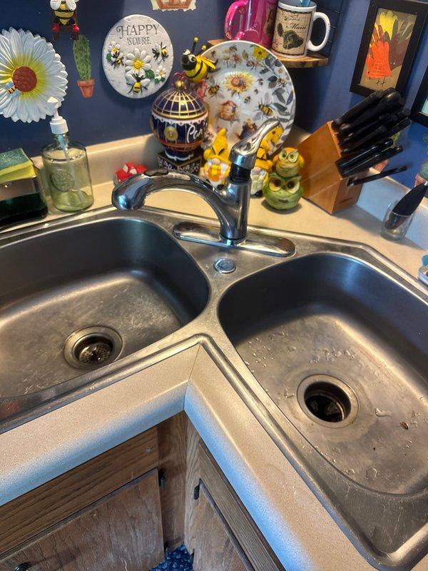 Responded to service call for malfunctioning kitchen faucet. Upon arrival, assessed the existing black single-handle faucet on double-basin stainless steel sink and determined replacement was necessary. Installed new faucet assembly and added stop valves to provide proper water shut-off capability for future maintenance. Tested installation to ensure proper operation and verified no leaks at connections.