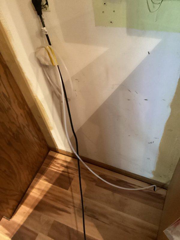 Replaced defective refrigerator water supply line with new line to restore proper water flow to the appliance. Installation completed in unfinished interior space with exposed wiring and construction materials present.