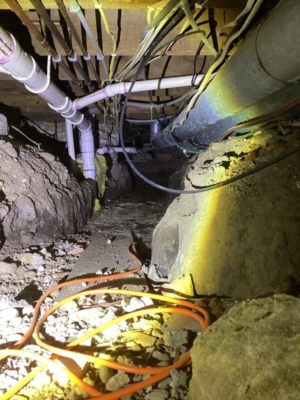 Responded to service call for kitchen sink gurgling when toilet flushes and standing water under pipes with possible sewage leak. Upon inspection, located active leak from drain line above ground in crawl space area of basement. Documented conditions with photographs showing compromised drainage piping and deteriorating foundation elements. Additionally identified dried out stand pipe in basement contributing to sewer gas odor throughout the space. Due to the scope of work required for proper drain line repair and cleaning, provided referrals to specialized drain service contractors including Rochester Drain Rite, Jetter Clean, Roto Rooter, and Mr. Rooter for comprehensive drainage system evaluation and remediation.