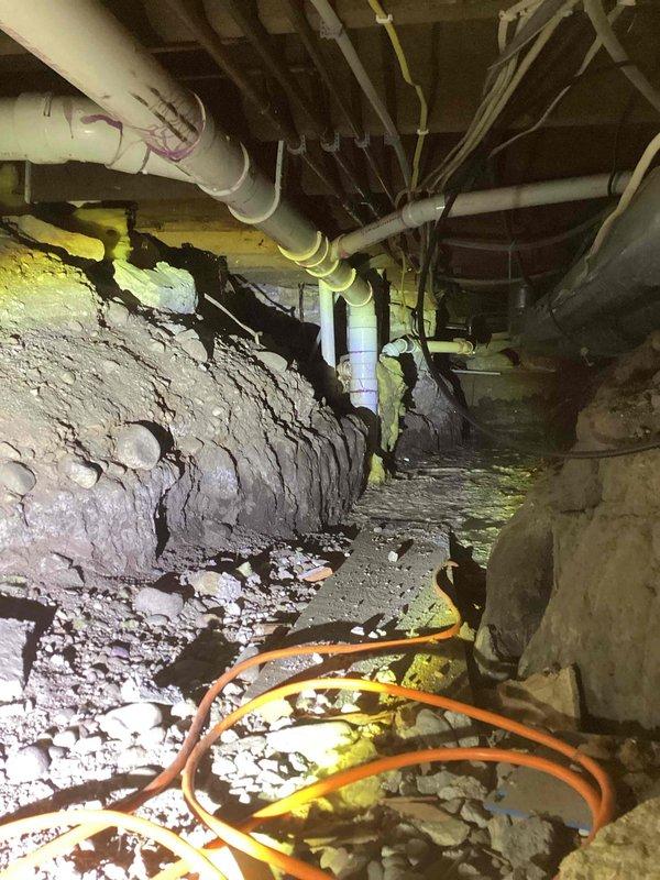 Responded to service call for kitchen sink gurgling when toilet flushes and standing water under pipes with possible sewage leak. Upon inspection, located active leak from drain line above ground in crawl space area of basement. Documented conditions with photographs showing compromised drainage piping and deteriorating foundation elements. Additionally identified dried out stand pipe in basement contributing to sewer gas odor throughout the space. Due to the scope of work required for proper drain line repair and cleaning, provided referrals to specialized drain service contractors including Rochester Drain Rite, Jetter Clean, Roto Rooter, and Mr. Rooter for comprehensive drainage system evaluation and remediation.