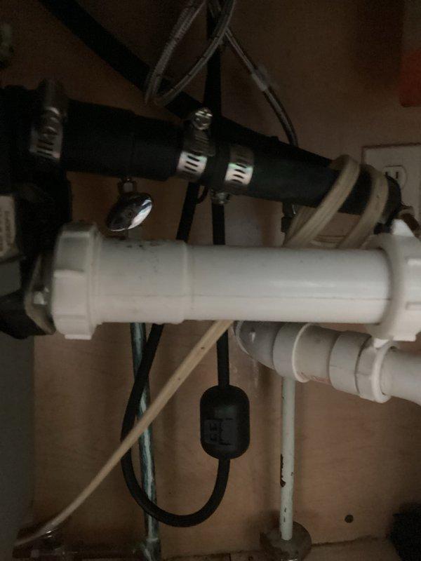 Responded to water accumulation in mechanical room and kitchen drainage issues. Upon inspection, discovered the water softener drain line had disconnected from the floor drain cover, causing water discharge onto the floor during regeneration cycles. Additionally, identified a pinched dishwasher drain line and blockage in the drainage system preventing proper discharge. Reconnected the water softener drain line to the floor drain cover, cleared the blockage from the dishwasher drain line, and installed a new dishwasher drain connection fitting to the garbage disposal. Tested all systems to verify proper drainage and operation. All plumbing fixtures now functioning correctly with no further leakage.