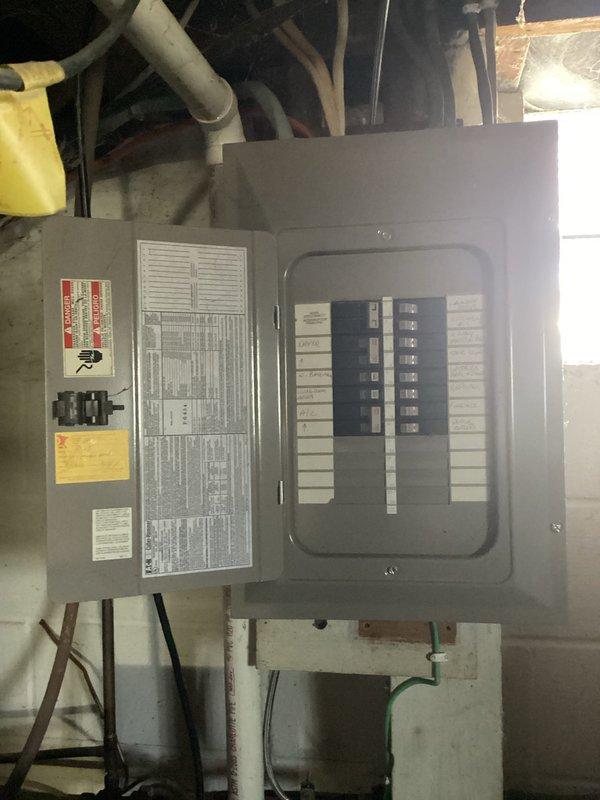 Completed site assessment for new electrical outlet installation in unfinished basement utility area. Evaluated existing electrical panel configuration and circuit capacity to determine optimal connection point for additional outlet. Assessed workspace conditions including concrete block walls, exposed ceiling joists, and available routing paths for new wiring installation.