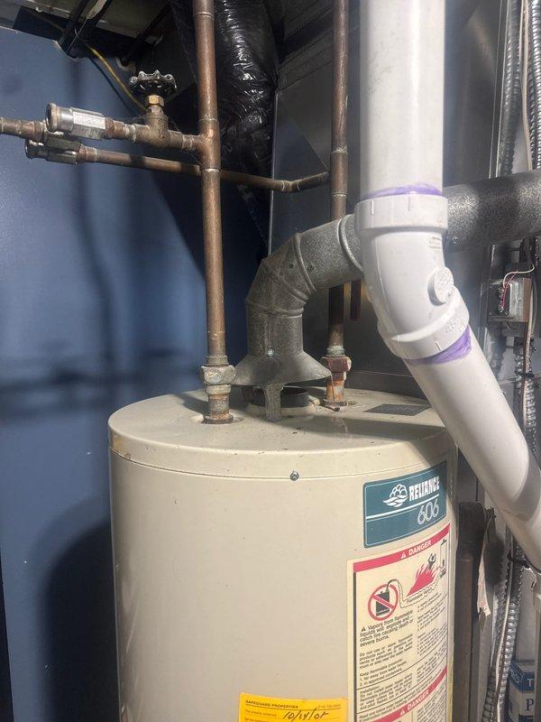 Responded to service call for leaking tanked water heater. Upon arrival, inspected the unit and confirmed active leak originating from the tank itself, which is not repairable. Provided estimate for complete water heater replacement with new Reliance 606 model unit. Replaced the failed water heater with new tanked unit, including all necessary connections to existing copper supply lines and PVC drain piping. Installed proper fittings and transition connections at top of unit, ensuring secure water inlet and outlet connections with shut-off valve access for future maintenance.
