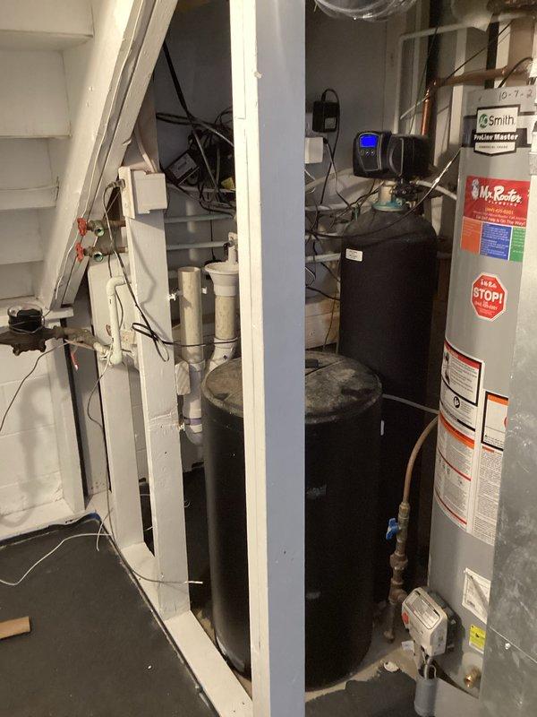 Completed installation of customer-supplied water treatment system including sediment filter and water softener unit in basement utility area. Connected black cylindrical water softener tank with digital control head to existing copper plumbing infrastructure using appropriate fittings and shut-off valves. Integrated sediment pre-filter into water supply line upstream of softener to protect system components and extend equipment lifespan. All connections properly secured and tested for leaks, with system positioned adjacent to existing water heater for optimal space utilization and plumbing efficiency.