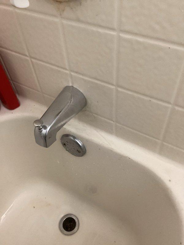 Responded to upstairs shower leak causing water damage to ceiling in bathroom below. Diagnosed faulty tub spout with diverter that leaked when shower function was engaged. Removed defective tub spout assembly and installed new replacement unit. Tested both tub and shower operations to verify complete leak elimination. Applied caulking around tub spout perimeter to ensure proper seal and prevent future moisture intrusion.