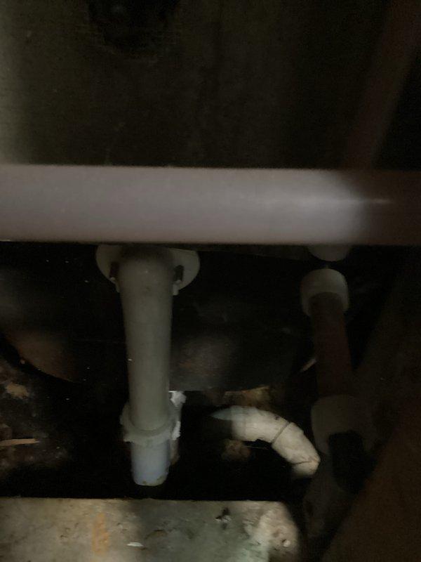 Responded to service call regarding reported drum trap and potential leak in older building. Upon arrival, performed thorough inspection of plumbing system behind wall access opening. Customer initially believed property had drum trap requiring assessment, but inspection revealed standard PVC trap configuration instead. Examined all visible plumbing components including white PVC drainage pipes, copper supply lines, and shut-off valves with blue handles. Inspected P-trap assembly beneath sink fixture and tested all connections for moisture or active leaks. No leaks detected in drainage system or supply lines. Confirmed all plumbing connections were secure and functioning properly with no water intrusion present.