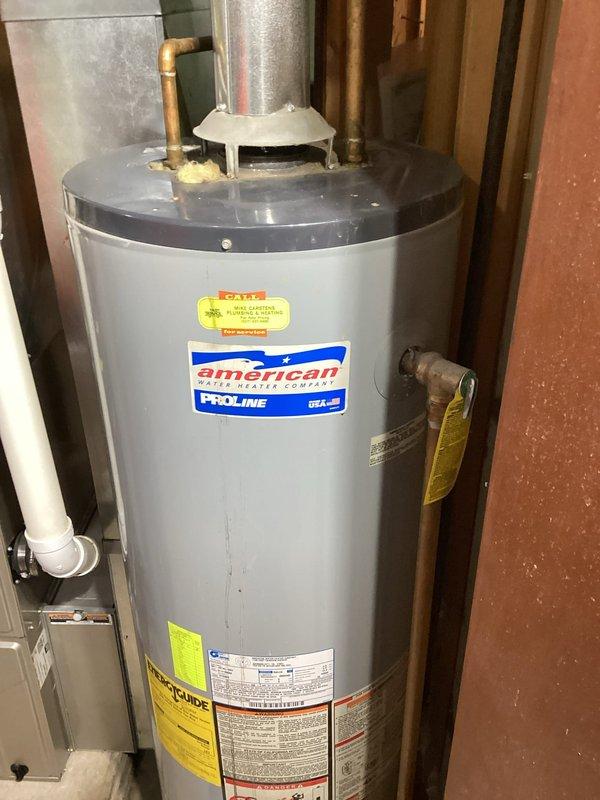 Provided estimate for replacement of existing water heater with a new 40-gallon standard vent natural gas unit. Assessed installation location in utility room, evaluated existing venting configuration, gas line connections, and water supply piping to determine scope of replacement work. Documented current American Water Heater Company ProLine unit and surrounding mechanical infrastructure including copper supply lines, pressure relief valve, gas valve assembly, and metal flue pipe connection for proper sizing and replacement specifications.