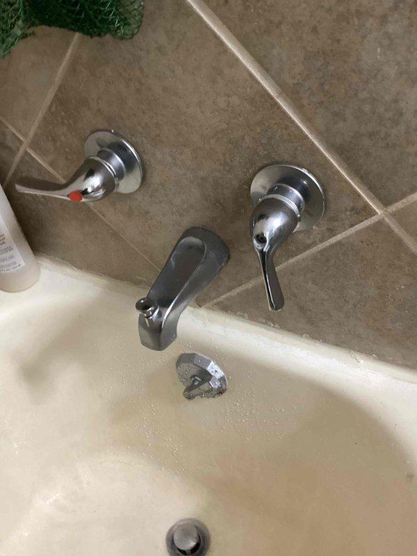Responded to service call for malfunctioning shower handles in hallway bathroom. Upon inspection, determined the cold water handle was stripped and spinning freely without engaging the valve cartridge. The handle screw was turning the cartridge itself rather than operating the valve mechanism properly. Documented the condition with photographs and advised that repair may require accessing the two-handle valve from the opposite side of the wall, which would necessitate dishwasher removal. Recommended scheduling a follow-up appointment with additional technician support to assess alternative repair options before proceeding with wall access work.