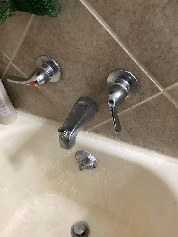 Responded to service call for malfunctioning shower handles in hallway bathroom. Upon inspection, determined the cold water handle was stripped and spinning freely without engaging the valve cartridge. The handle screw was turning the cartridge itself rather than operating the valve mechanism properly. Documented the condition with photographs and advised that repair may require accessing the two-handle valve from the opposite side of the wall, which would necessitate dishwasher removal. Recommended scheduling a follow-up appointment with additional technician support to assess alternative repair options before proceeding with wall access work.