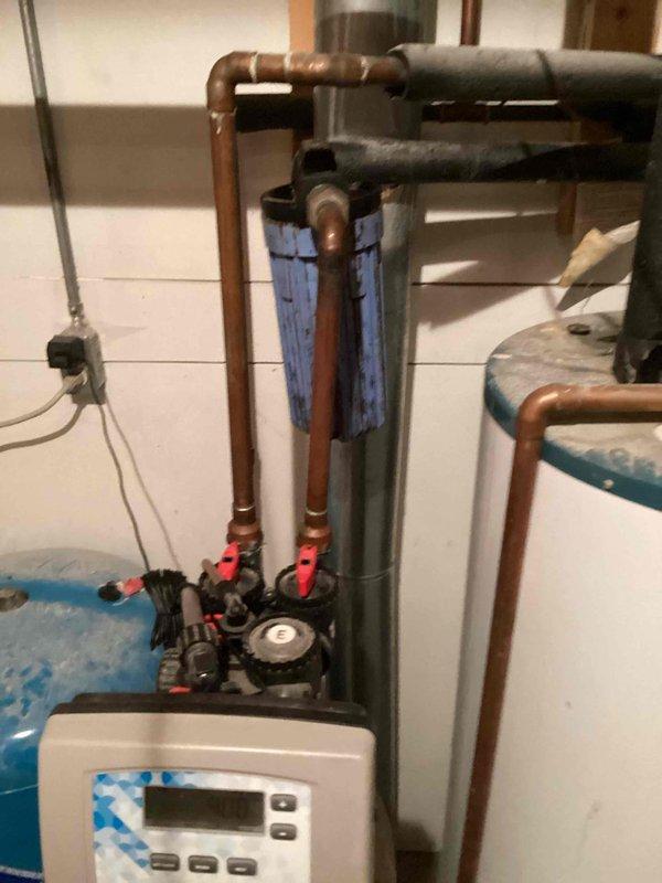 Responded to service call for rust-colored water throughout entire residence supplied by well water system. Conducted on-site inspection of existing water treatment equipment and plumbing infrastructure, documenting current configuration including water softener unit, pressure tank, and filtration system. Assessed water quality issues and determined high iron content in well water with no existing iron filtration system installed. Photographed mechanical room setup showing current plumbing arrangement, copper piping, existing blue filter cartridge, water heater, and treatment equipment. Prepared and provided detailed estimate for installation of new iron filter system to address elevated iron levels and eliminate rust discoloration in household water supply.