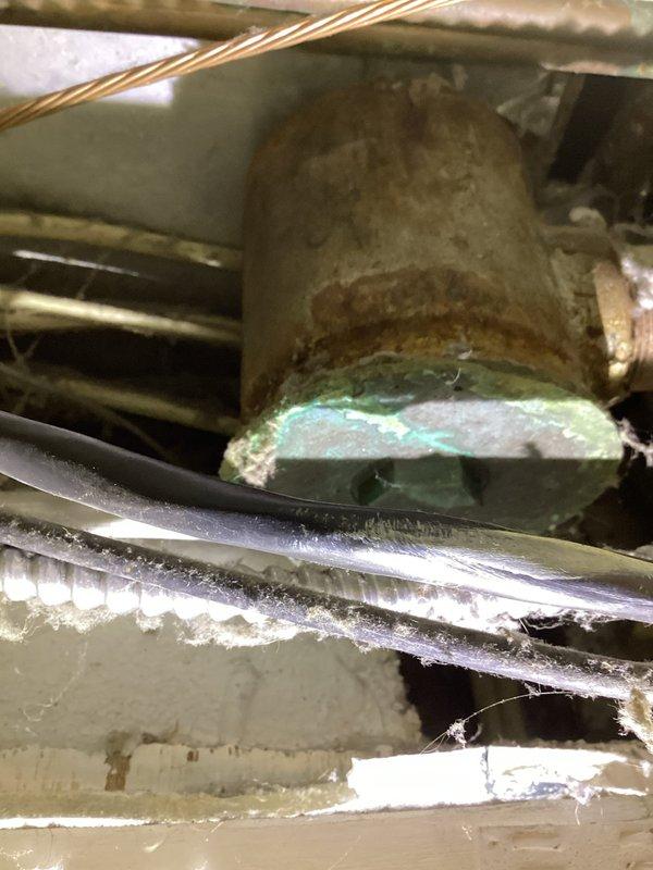 Responded to service call for drum trap replacement on bathtub drainage system. Upon inspection, found heavily corroded drum trap with significant rust deterioration and mineral buildup in confined space adjacent to HVAC ductwork. Previous jetter cleaning service had cleared the blockage but recommended permanent replacement with modern P-trap configuration. Assessed extremely limited access conditions due to proximity of air conditioning duct, which may require relocation for proper drum trap removal. Documented existing conditions showing advanced corrosion on trap body and mineral deposits on connecting pipes. Provided estimate for complete drum trap removal and new P-trap installation to upgrade drainage system to current plumbing standards and prevent future blockages.