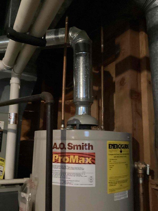 Responded to service call for no hot water condition at residential property. Upon inspection, found A.O. Smith ProMax tanked water heater actively leaking through the tank itself, indicating internal tank failure. Confirmed leak was not from fittings, connections, or pressure relief valve, but from compromised tank integrity. Documented existing installation including copper supply lines, PVC drainage piping, and metallic flue connections in utility space with exposed framing. Explained to property owner that tank leaks are non-repairable and require complete unit replacement. Provided verbal estimate for water heater replacement and discussed scheduling options for installation.