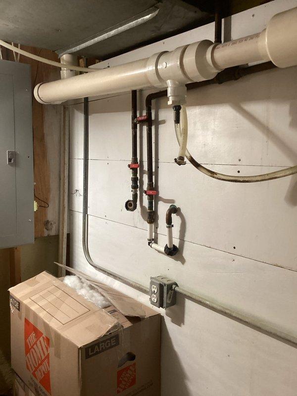 Completed installation of water treatment system in basement utility area. Installed black iron piping with multiple red-handled shut-off valves, connected copper supply lines, and integrated flexible discharge hose into existing plumbing infrastructure. All connections tested and system operational upon completion.