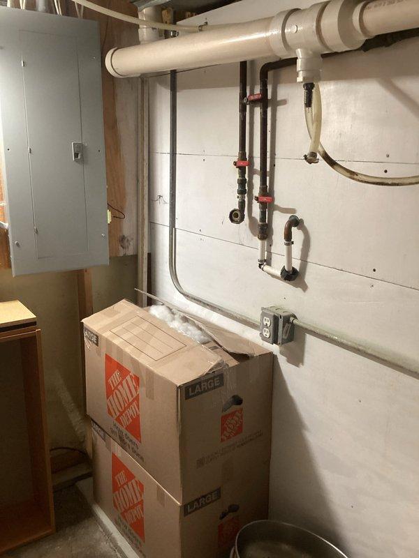 Completed installation of water treatment system in basement utility area. Installed black iron piping with multiple red-handled shut-off valves, connected copper supply lines, and integrated flexible discharge hose into existing plumbing infrastructure. All connections tested and system operational upon completion.