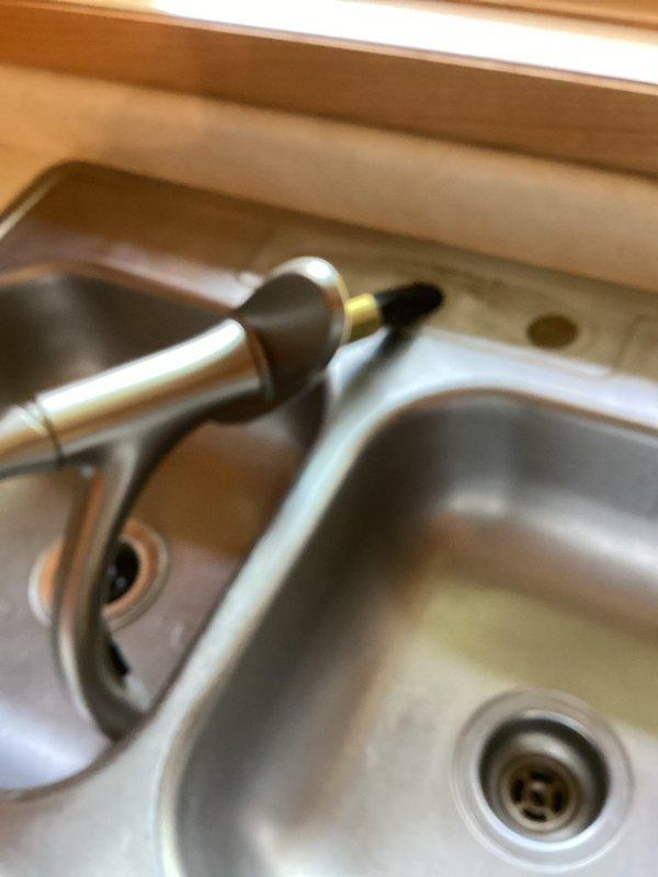 Removed existing kitchen faucet from double-basin stainless steel sink and installed new customer-supplied pull-down faucet with brushed nickel finish. Completed all plumbing connections, verified proper water flow and temperature control operation, and tested spray head functionality. All fixtures operating correctly with no leaks detected upon final inspection.