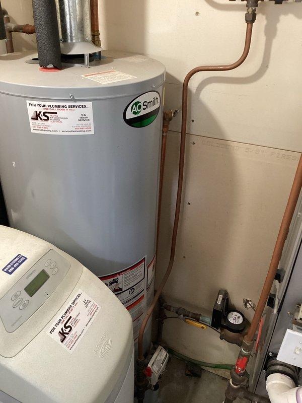 Responded to service call for leaking water heater. Upon arrival, assessed AO Smith tanked water heater and confirmed active leak requiring full unit replacement. Removed existing failed water heater and installed new AO Smith residential water heater unit with proper venting through ceiling exhaust system. Connected copper supply lines with appropriate shut-off valves and pressure relief valve. Installed insulated hot and cold water lines and verified all connections to existing plumbing manifold system. Ensured proper clearances around water softener unit and coordinated piping configuration with existing pressure gauge and water meter. Tested all connections for leaks, verified proper venting operation, and confirmed water heater functionality before completing installation.