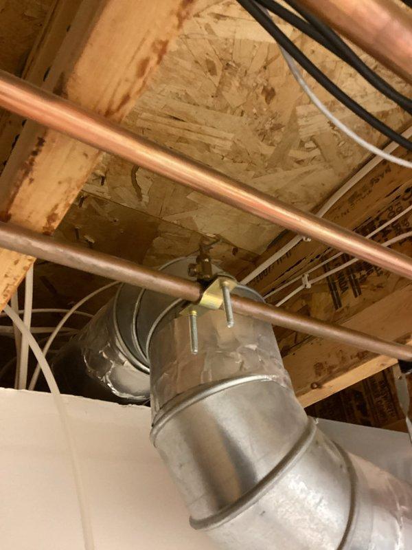 Responded to a water leak emergency involving a damaged 1/4" refrigerator supply line running from the mechanical room to an upstairs kitchen. Upon arrival, identified multiple pinhole leaks, cracks, and breaks in the plastic supply tubing routed through the ceiling joists. Immediately shut off the needle valve at the source in the mechanical room to stop active water flow and prevent further damage. Disconnected the compromised supply line from the valve to isolate the system. The faulty supply line will require complete replacement from the mechanical room shutoff valve to the refrigerator connection point. Documented existing plumbing infrastructure including copper water lines and HVAC ductwork in the exposed ceiling area for reference during future repair work.