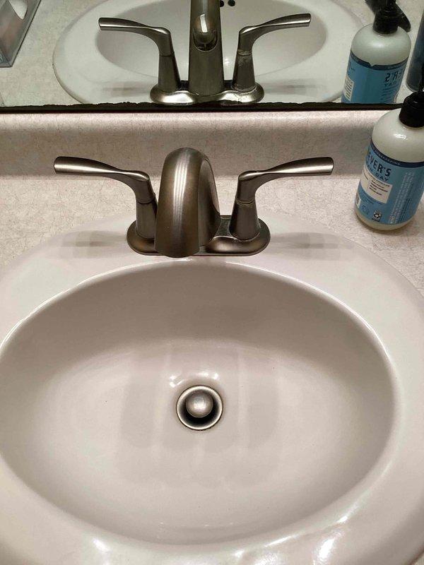 Responded to clogged drain service call for upstairs bathroom vanity. Upon arrival, completed drain cleaning procedure that had been previously started, reassembling the drain system after snake removal. Installed new pop-up drain assembly with matching metallic finish to coordinate with existing brushed nickel faucet. Verified proper installation of P-trap and all drain connections beneath sink. Conducted water flow test to confirm drainage functionality and inspected all connections for leaks with no issues detected.
