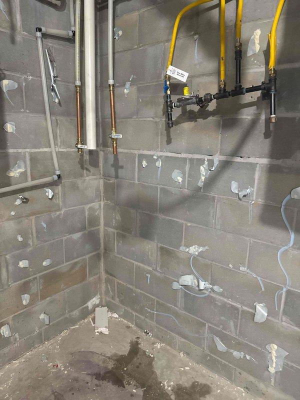Responded to service call with scheduled arrival between 12-4 PM. Successfully disconnected and relocated water heater and water softener to center of room as requested. Removed water heater, water softener, and iron filter from utility area. Work completed in unfinished basement space with existing plumbing infrastructure including PVC, copper piping, and gas line assembly remaining in place.