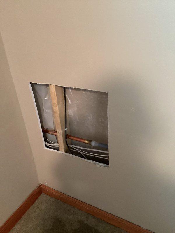 Responded to a water leak caused by a burst outdoor spigot that was leaking into the interior walls when in use. Accessed the affected area through an interior wall opening, disconnected and removed the failed outdoor faucet, and installed a new replacement unit. Restored water service to the home and verified proper operation with no leaks detected.