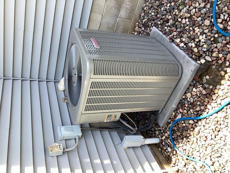 Responded to service call for loud fan noise on residential AC unit. Upon inspection, identified loose side panel causing vibration and rattling sounds. Secured panel and discovered unit was low on refrigerant charge. Checked system pressures and confirmed refrigerant leak present. Documented equipment condition with photos showing outdoor condenser unit installation, surrounding components, and overall system layout. Presented customer with repair options including leak detection/repair with refrigerant recharge versus full system replacement based on age and condition of equipment.