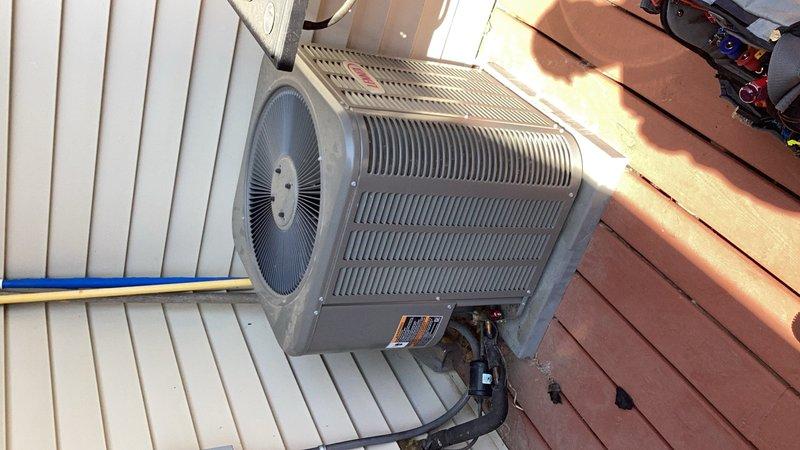 Responded to no cooling complaint on outdoor condensing unit. Upon arrival, performed diagnostic evaluation and determined system was low on refrigerant charge. Documented equipment condition with photos showing aged gray condenser unit with horizontal louvered panels positioned on wooden deck against building exterior. Provided repair estimate to address refrigerant loss and coordinated with project manager for approval to proceed with necessary repairs.