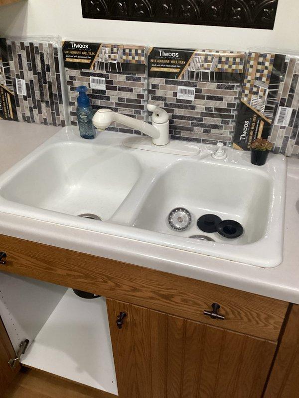 Completed faucet replacement on white double-basin kitchen sink, installing new white single-handle faucet with proper connection to existing copper supply lines and shut-off valves. Provided estimate for future sink replacement and consulted on backsplash tile options currently being evaluated for kitchen renovation.