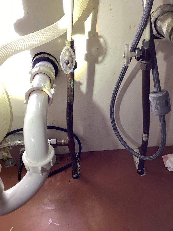Responded to a leak under the kitchen sink caused by a corroded galvanized nipple extending from the wall connection for the left side drain assembly. Upon inspection, discovered a small hole in the bottom of the galvanized nipple due to corrosion. Removed the deteriorated nipple from the wall fitting and thoroughly cleaned the threads, which showed significant corrosion buildup. Installed a trap adapter to the existing galvanized fitting and reassembled the drain assembly. Tested the system by running the faucet and confirmed proper drainage with no leaks detected.