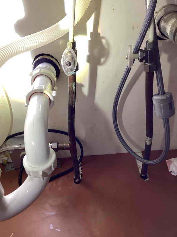 Responded to a leak under the kitchen sink caused by a corroded galvanized nipple extending from the wall connection for the left side drain assembly. Upon inspection, discovered a small hole in the bottom of the galvanized nipple due to corrosion. Removed the deteriorated nipple from the wall fitting and thoroughly cleaned the threads, which showed significant corrosion buildup. Installed a trap adapter to the existing galvanized fitting and reassembled the drain assembly. Tested the system by running the faucet and confirmed proper drainage with no leaks detected.