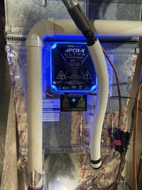Installed APO-X ULTRA air treatment system with UV light technology into existing HVAC ductwork. The blue-lit purification unit was professionally mounted to the metal plenum with proper safety labeling and integrated with the Lennox furnace system to provide whole-home air sterilization.