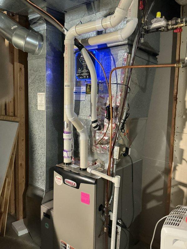 Installed APO-X ULTRA air treatment system with UV light technology into existing HVAC ductwork. The blue-lit purification unit was professionally mounted to the metal plenum with proper safety labeling and integrated with the Lennox furnace system to provide whole-home air sterilization.