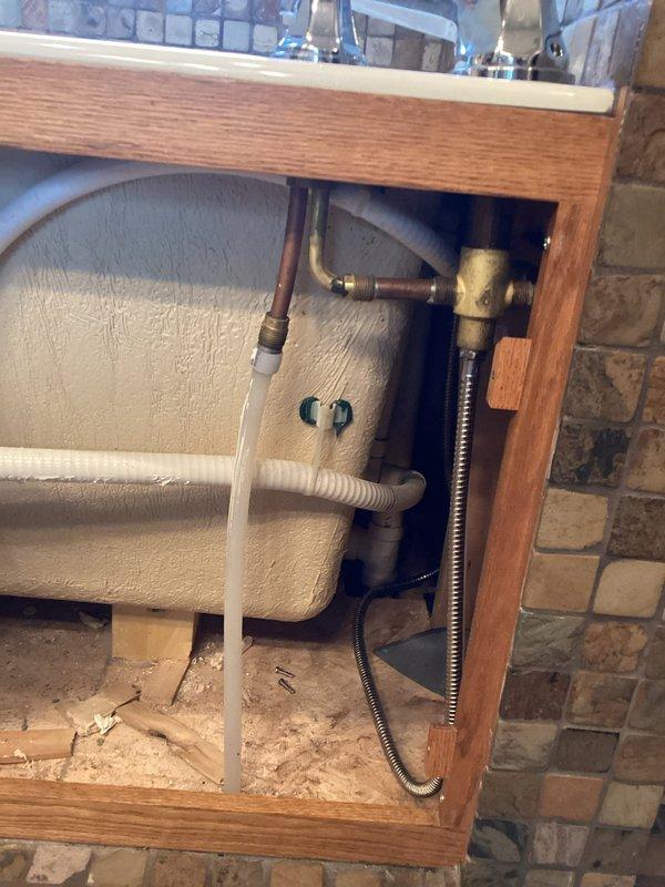 Completed installation of bathroom fixtures including roman-style faucet assembly with chrome finish and white porcelain sink basin. Connected all water supply lines with shut-off valves, installed P-trap drainage assembly with corrugated drain pipe, and verified proper operation of all plumbing connections beneath vanity cabinet.