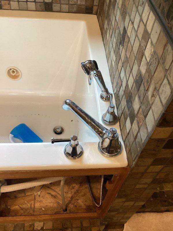 Completed installation of bathroom fixtures including roman-style faucet assembly with chrome finish and white porcelain sink basin. Connected all water supply lines with shut-off valves, installed P-trap drainage assembly with corrugated drain pipe, and verified proper operation of all plumbing connections beneath vanity cabinet.