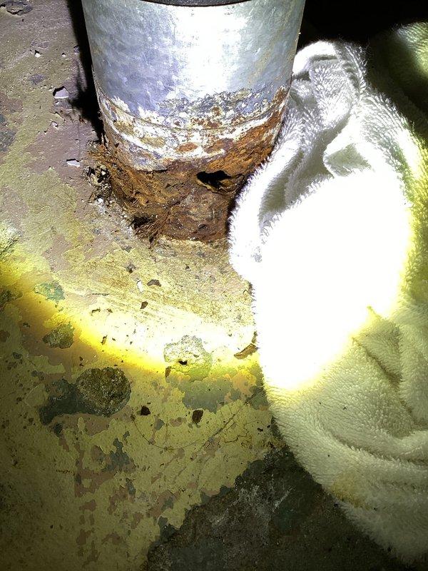 Responded to service call for leaking cast iron drain line. Upon inspection, discovered a quarter-sized hole in the 4" cast iron drain pipe near floor level, with an additional 6-8 inches of severely corroded pipe extending toward the slab foundation. The corroded section exhibited significant deterioration with rust and structural compromise requiring replacement. Documented the damage with photographs showing the extent of corrosion at the pipe base and water damage to the surrounding floor area. Due to the location of the damaged section entering the slab, concrete floor demolition will be necessary to access and replace the affected drain line. Forwarded all inspection findings and photographic documentation to schedule follow-up appointment for the required excavation and pipe replacement work.