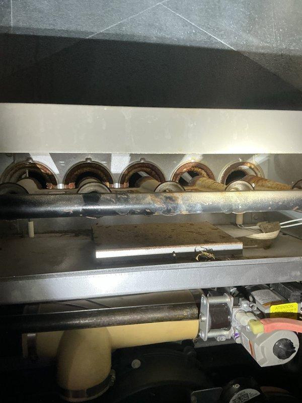 Performed routine furnace tune-up and discovered burners with significant rust and oxidation preventing proper ignition. Documented equipment condition with photographs showing corroded burner assemblies and discolored circular openings. Provided estimate for burner replacement, which was approved for future repair.